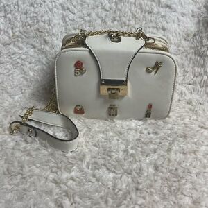 White synthetic leather crossbody bag with fashion accents & gold tone chain.